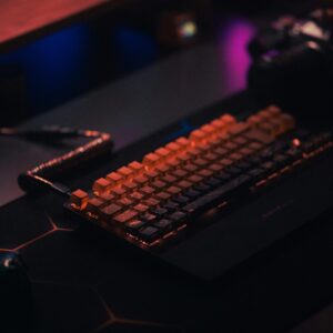 Home Close-up of a backlit mechanical keyboard on a dark desk, ideal for gaming setups.